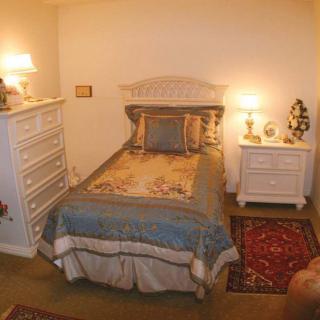 A cozy bedroom with a bed, nightstand, dresser, and decorative lamps.