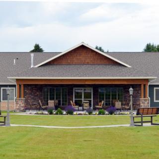 A modern building with a large lawn and benches in front.