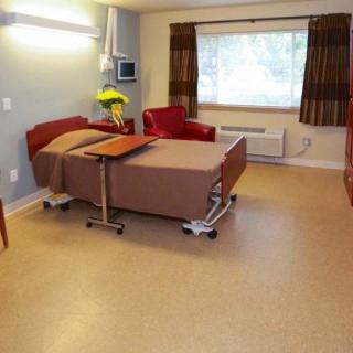 A clean and well-lit hospital room with a bed, chair, and medical equipment.