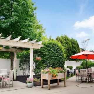 A beautiful outdoor patio featuring a pergola, seating area, and lush greenery.