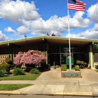 A mid-century building with an American flag in front under a blue sky with clouds.