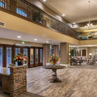 A spacious and elegantly decorated hotel lobby with wood flooring, comfortable seating, and floral arrangements.
