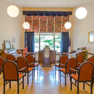 A serene interior setting designed for gatherings or ceremonies, featuring seating and decorative elements.