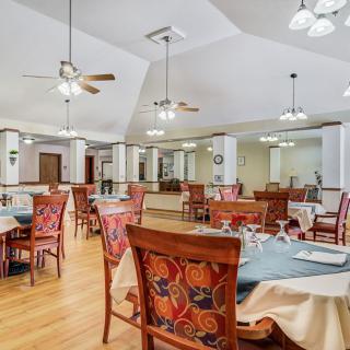 Spacious dining area with elegantly set tables and decorative chairs.
