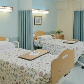 A clean and organized hospital room with two beds and privacy curtains.