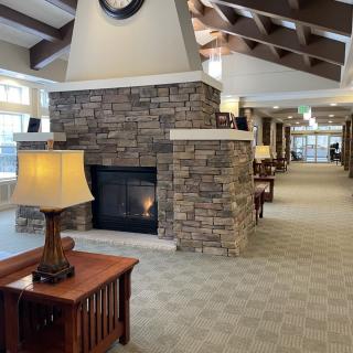 A cozy interior hallway featuring a stone fireplace, wooden furniture, and ceiling beams.