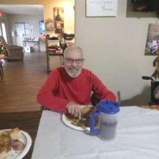 An elderly man enjoying a meal in a cozy dining setting.
