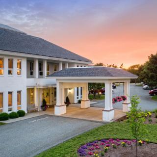 A scenic view of a building entrance at sunset with a landscaped driveway.