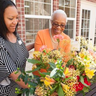 Two women enjoy arranging a colorful assortment of flowers together outside.