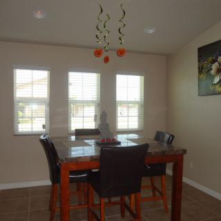 A cozy dining room with a table and chairs, illuminated by natural light from the windows.