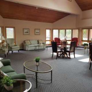 A spacious living room with sofas, chairs, and coffee tables, featuring large windows that let in natural light.