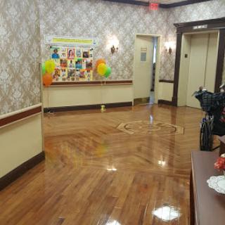 A well-decorated hallway featuring wooden floors and colorful balloons, leading to elevators.