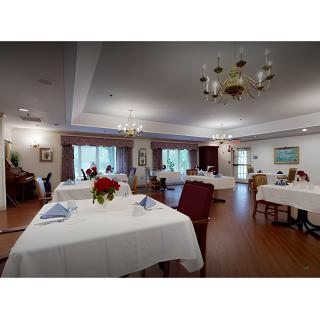 A neatly arranged dining room with tables covered in white tablecloths, adorned with decorative flowers and illuminated by chandeliers.