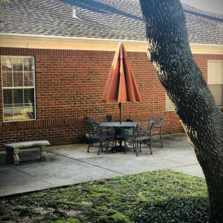 A cozy outdoor patio area with a table, chairs, and an umbrella next to a brick building.