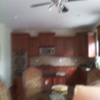 Blurred image of a kitchen with wooden cabinets and dining area.