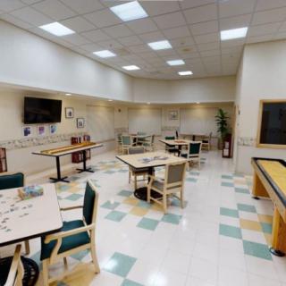 A spacious indoor dining area with tables and chairs, featuring a television on the wall.
