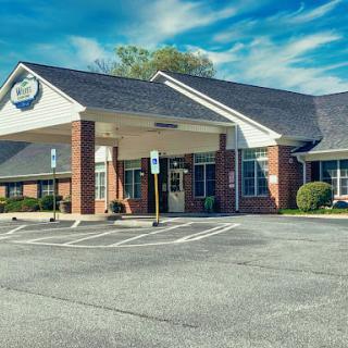 A well-maintained commercial building with a spacious parking lot under a clear blue sky.