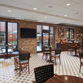 A modern cafe interior with brick walls, tables, and chairs.