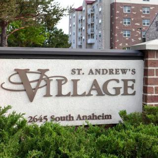 Entrance sign for St. Andrew's Village, located at 2645 South Anaheim with buildings in the background.