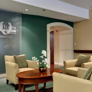 A cozy lobby seating area featuring comfortable chairs and a wooden table, accented by a green wall and decorative plants.