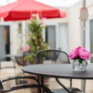 A cozy outdoor patio setting with a table, chairs, and pink flowers in a vase.