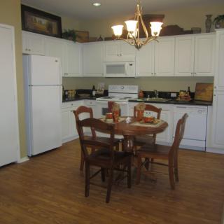 A cozy kitchen and dining area featuring white cabinets, a wooden dining table set, and a chandelier.