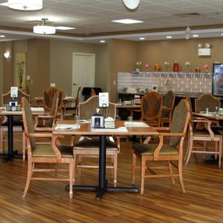 A spacious dining area with wooden tables and chairs, featuring warm lighting and a cozy atmosphere.