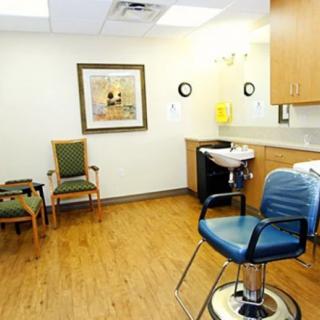 A cozy salon interior featuring a barber chair, waiting chairs, and hair washing sink.