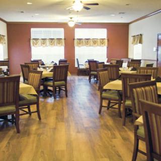 An empty restaurant dining room with neatly arranged tables and chairs on a hardwood floor.
