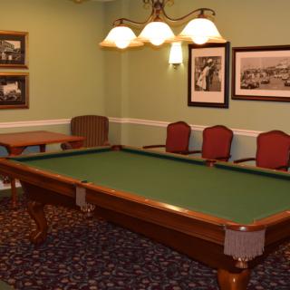A cozy game room featuring a classic pool table, elegant lighting, and vintage wall art.