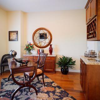 A cozy dining room with a wooden table and chairs, adorned with a decorative mirror, plants, and a cabinet.