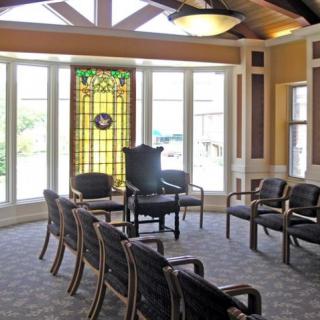 A well-lit waiting room with arranged chairs and a decorative stained glass window.