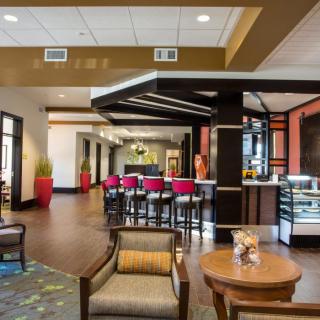 A modern lobby area featuring a cafe with bar stools and seating arrangements.