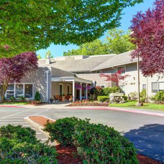 A well-maintained building entrance surrounded by lush landscaping and colorful trees on a sunny day.
