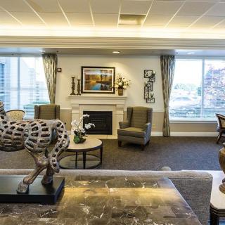 A beautifully decorated living room featuring a central fireplace, stylish furniture, and a striking sculpture.
