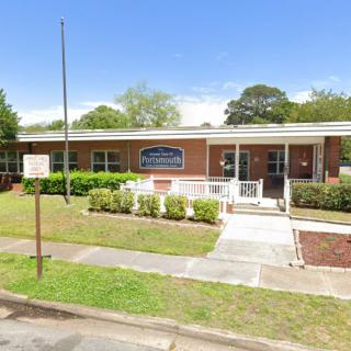 A single-story brick school building with a front yard and sidewalk.