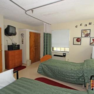 A hospital room with two beds, a television, and wall decorations.