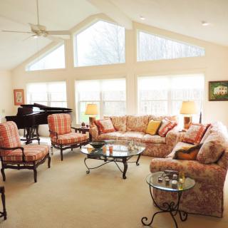 A spacious living room with a grand piano, cozy seating area, and large windows allowing natural light to fill the space.