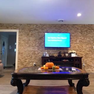 A cozy living room with a stylish stone accent wall, featuring a coffee table adorned with fruit decorations and a mounted TV.