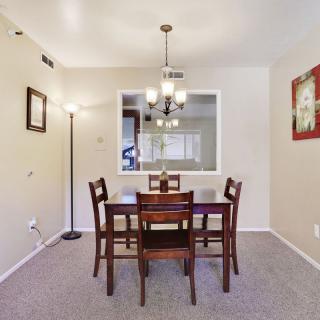 A cozy dining room with a wooden table and chairs, illuminated by a ceiling light fixture.