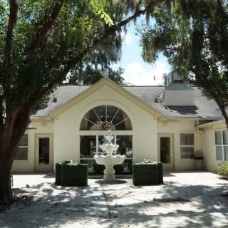A charming house with a central fountain surrounded by lush trees.