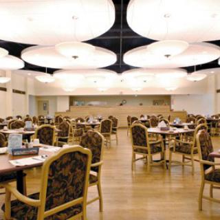 A spacious dining area with elegant lighting and neatly arranged tables and chairs.