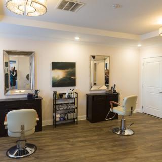A modern hair salon interior with stylish chairs and mirrors, featuring a wooden floor and wall art.
