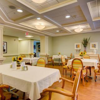 A neatly arranged dining room with tables and chairs, featuring elegant decor and warm lighting.