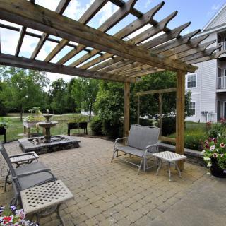 A serene backyard patio with a pergola and outdoor seating overlooking a fountain.
