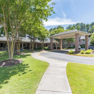 A well-maintained building entrance surrounded by green landscaping and trees on a sunny day.