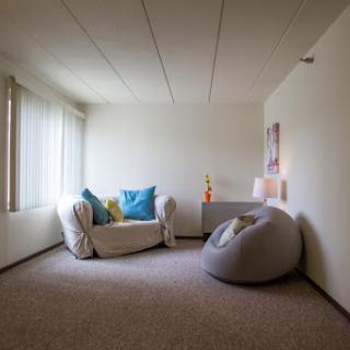 A minimalist living room featuring a cozy sofa with colorful cushions and a bean bag, bathed in natural light.