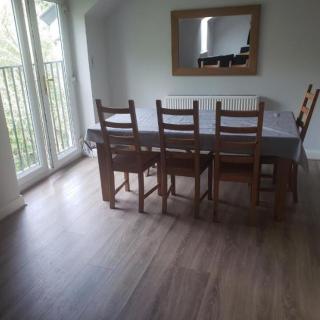 A dining room with a wooden table and chairs, featuring a large mirror on the wall and glass doors leading outside.