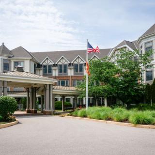 A large hotel building with a landscaped entrance and an American flag.
