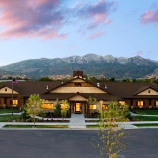 A beautifully designed residential building set against a stunning mountain backdrop at sunset.
